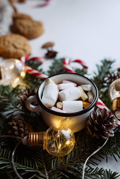 Chocolate or cocoa with marshmallow, cookies, candy and the garland on a dark background. - Фото, зображення