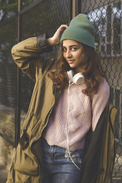 Πορτρέτο ενός χαριτωμένο μελαχρινή κοπέλα σε γυαλιά και ακουστικά σε ένα δρόμο της πόλης. - Φωτογραφία, εικόνα
