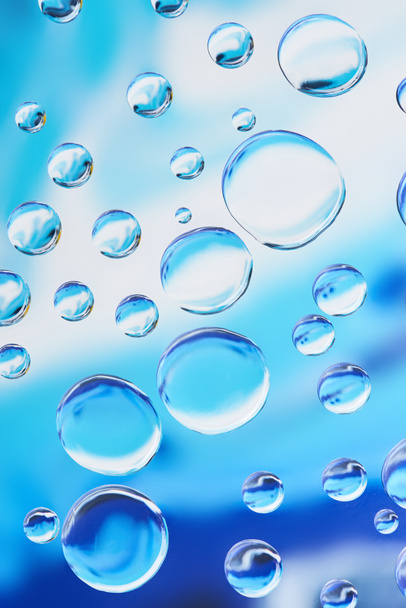 Nahaufnahme von schönen transparenten Wassertropfen auf blauem abstrakten Hintergrund - Foto, Bild