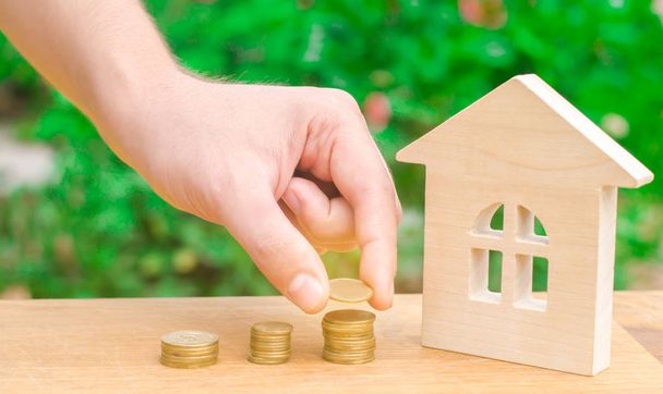 Concept investment in real estate. Saving money to buy a new home. Wooden house and stacks of coins from small to large. Buying, renting apartments. Mortgages and tax on housing / property - Φωτογραφία, εικόνα