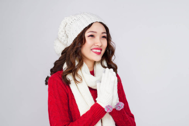 Jovem mulher asiática em camisola vermelha e chapéu posando no fundo claro
 - Foto, Imagem