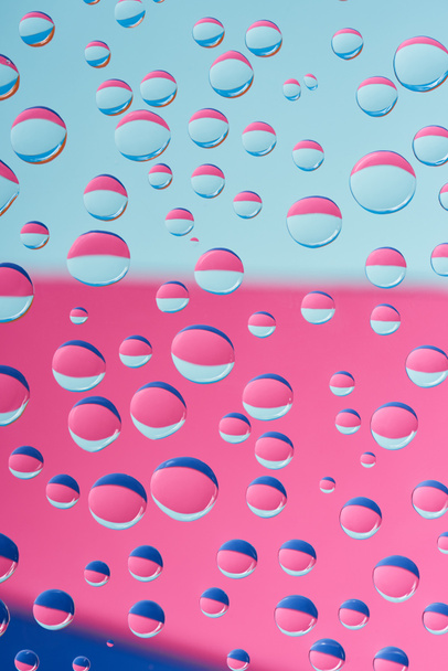 close-up view of transparent droplets on pink and blue abstract background  - Foto, afbeelding