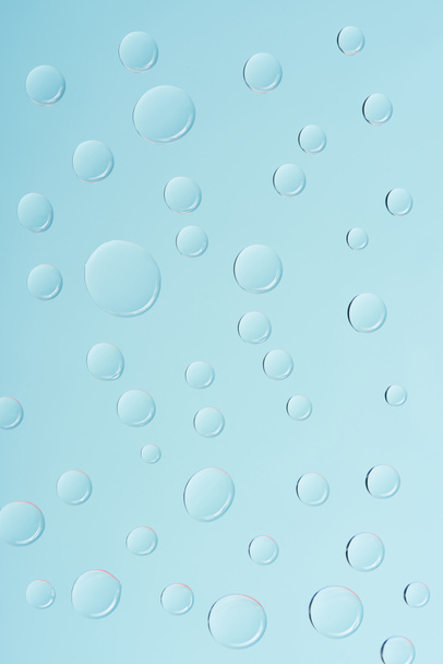 close-up view of transparent water drops on light blue background - 写真・画像