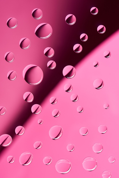 close-up view of transparent calm water drops on pink background        - Foto, immagini