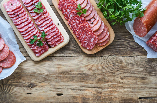 Sliced salami with parsley on a wooden cutting board                                - Photo, image