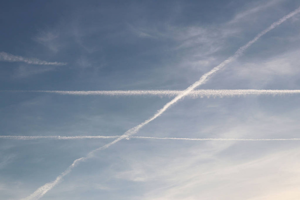  Air liner leaving a trace of exhaust gases glowing in the sun. Ecology of passenger traffic. Transport of goods by air. Intersection at an angle of two parallel lines. Euclidean geometry in the natur - Photo, Image