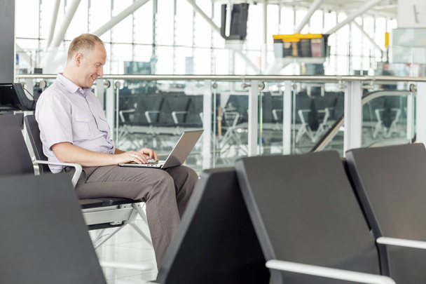 Bir uçak havaalanında beklerken onun dizüstü bilgisayarda çalışan adam - Fotoğraf, Görsel