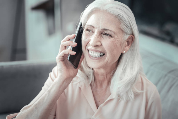 Cheerful aged woman holding her smartphone - Foto, Imagem