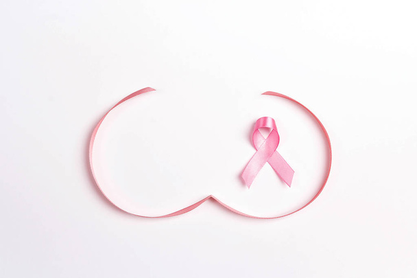 Рожева стрічка з символом форми грудей на білому тлі. Символ обізнаності про рак молочної залози. Жовтнева кампанія поінформованості
. - Фото, зображення