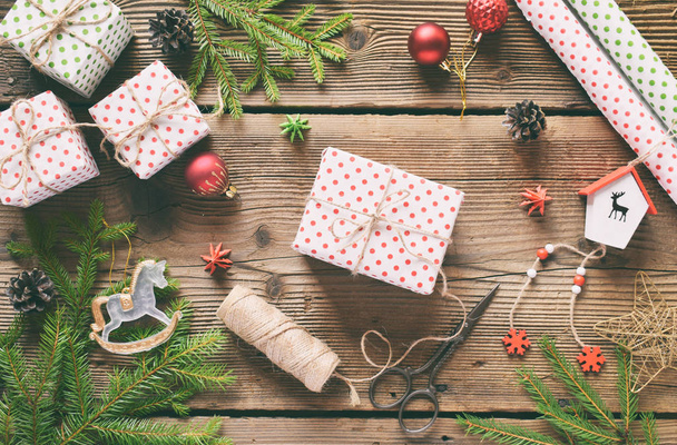 Gift wrapping. Christmas composition with present box, packing paper, festive decoration and fir tree branch. Preparation for holiday. Merry Christmas and Happy New Year concept - Foto, Imagen