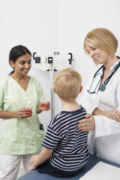 Doctor Looking At Boy While Nurse Standing With Medicine - Foto, Imagem