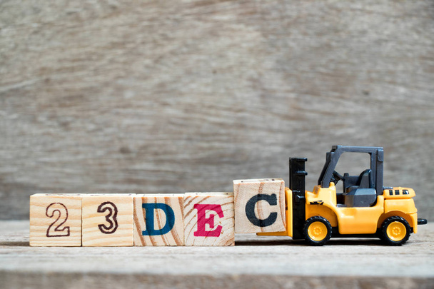 Toy forklift hold block c to complete word 23dec on wood background (Concept for calendar date 23 in month December) - Photo, Image