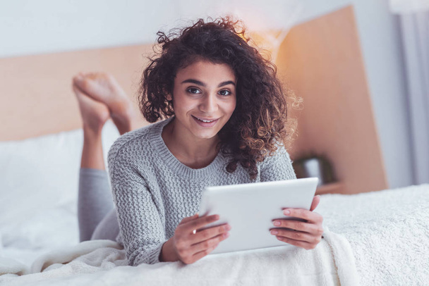 Modern girl reading electronic book lying in bed - Фото, изображение