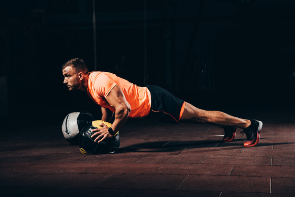attraente sportivo atletico che fa flessioni sulla palla medica in palestra scura
 - Foto, immagini