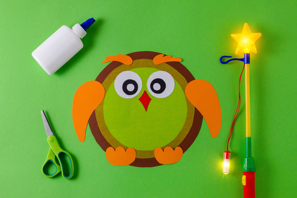 diy lantern for sankt martin day, traditional german feast, owl of color paper, glue, scissors, lanterns wand with light on green background - Photo, Image