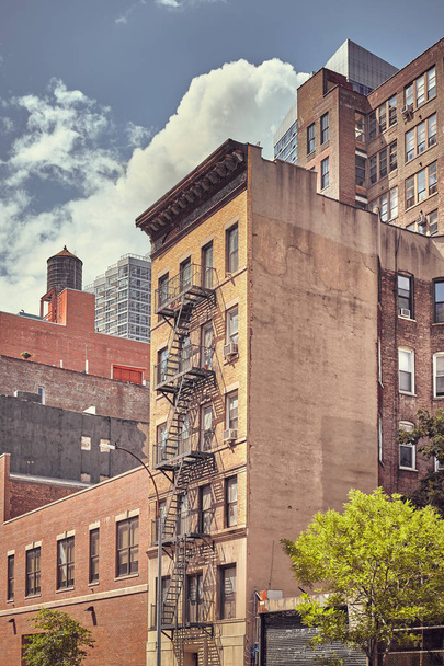Old building with fire escape in downtown New York, color toned picture, USA. - Фото, изображение