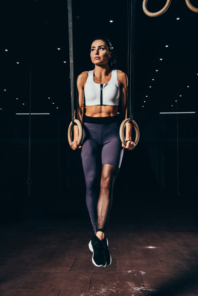 attractive athletic sportswoman exercising with gymnastic rings - Foto, afbeelding