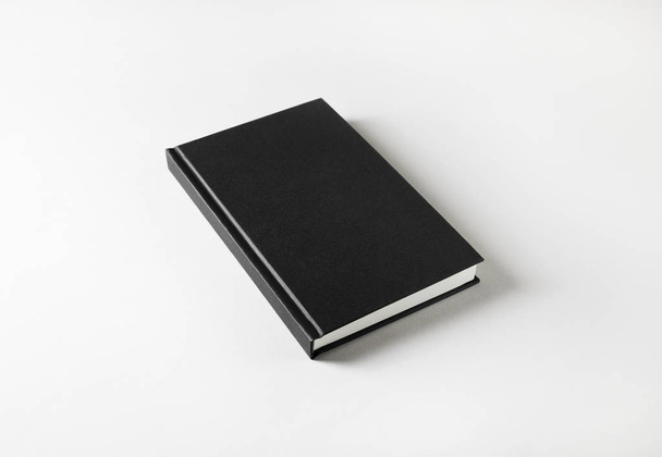 Zwart notitieboek dekking op wit papier achtergrond. - Foto, afbeelding