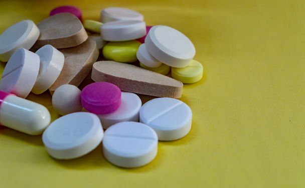 différentes pilules de couleur multy à partir d'une bouteille sur fond jaune
 - Photo, image