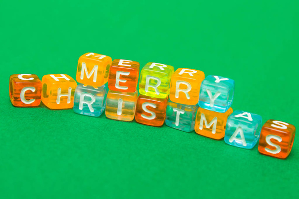 words merry christmas made of colorful blocks on green background. Flat lay, top view - holidays, winter, christmas and new year celebration concept - Photo, Image