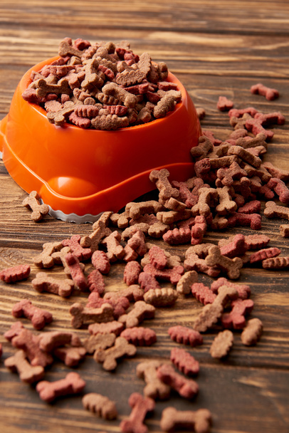 selective focus of plastic bowl with pile of dog food on wooden table  - 写真・画像