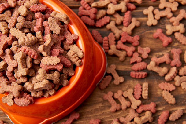 selective focus of plastic bowl with pile of dog food on wooden table  - Photo, Image