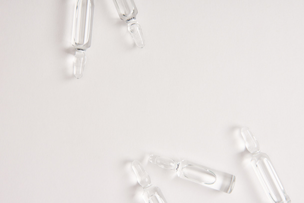 elevated view of ampoules with medical liquid on white surface  - 写真・画像