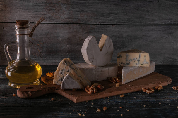 Still life of different types of cheese and nuts, honey, wine. Posted on a wooden stand - Photo, Image