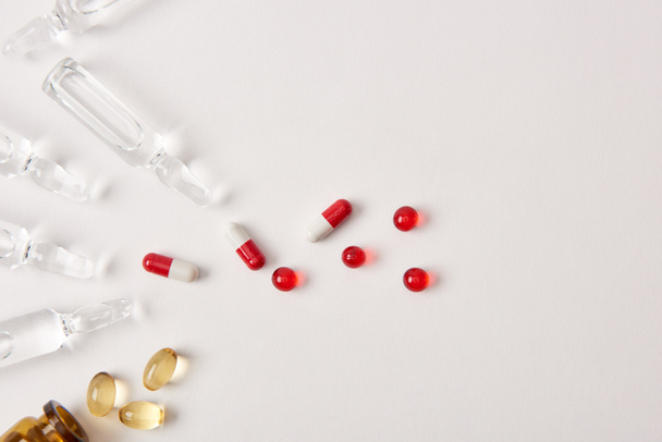 вид сверху различных таблеток и ампул с лекарствами на белой поверхности
  - Фото, изображение