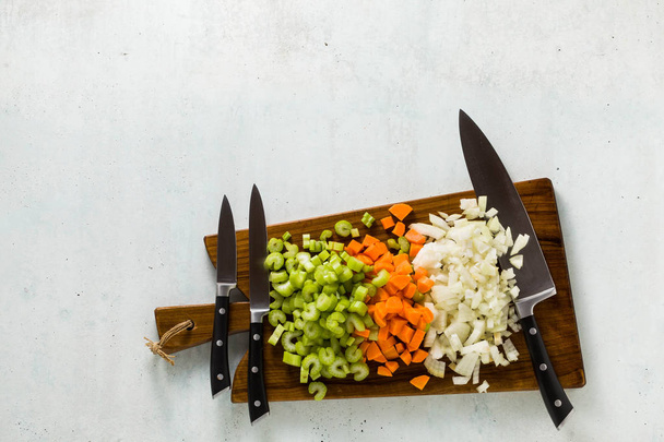 a set of knives on a wooden cutting board and chopped vegetables - Фото, изображение