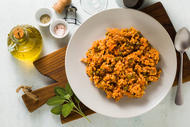 Italian risotto with tomato sauce and green peas, served in a plate on a wooden cutting board. classic Mediterranean cuisine. healthy vegan meal for the whole family - Photo, Image