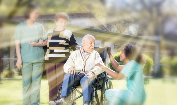 Zwei Ärztinnen helfen älteren Männern und Frauen mit körperlichen Behinderungen im Garten der Reha-Einrichtung mit Sonnenstrahlen. - Foto, Bild