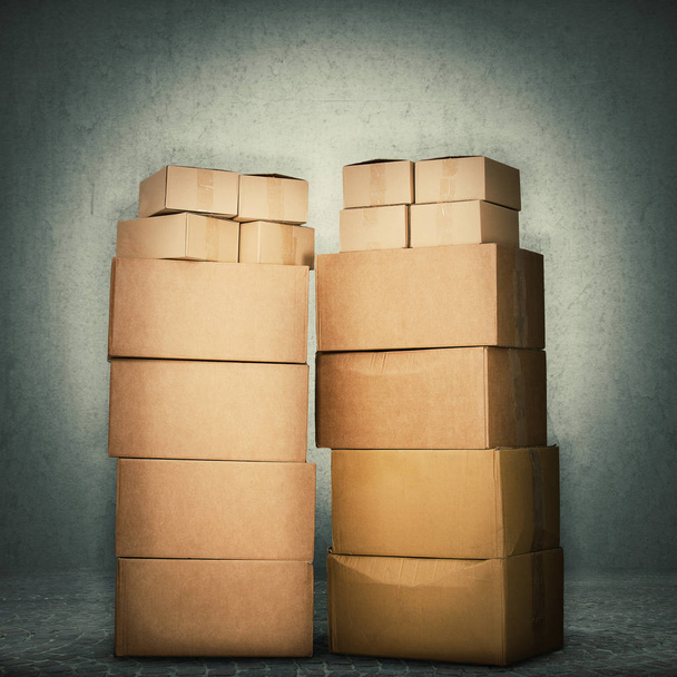 Stack of cardboard boxes full length isolated over grey wall concrete background. Delivery cargo warehouse storage concept. - Photo, Image