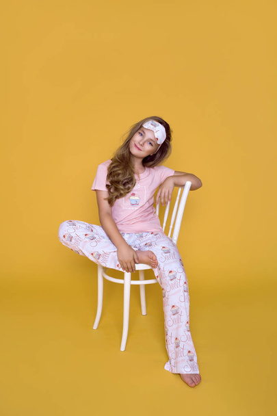 Beautiful young girl, in pajama on a yellow background in the studio. - Photo, Image