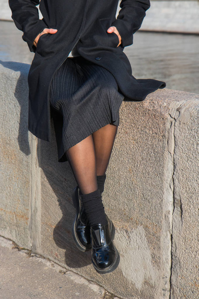 Girl sitting in fashionable shoes by the river - Foto, Imagen