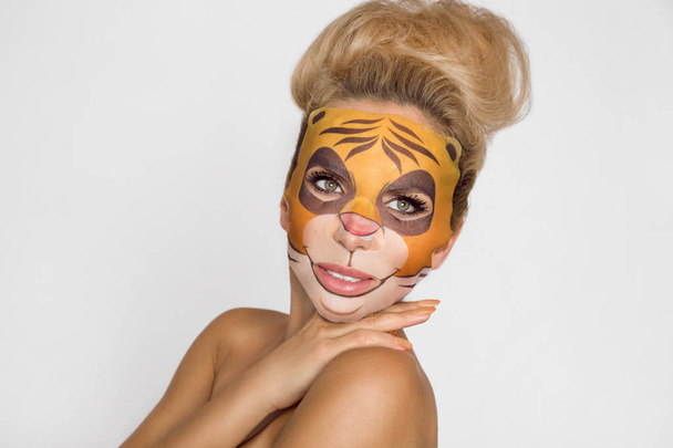 Beautiful woman with moisturizing leopard face mask. Mask with leopard, cat. - Photo, Image