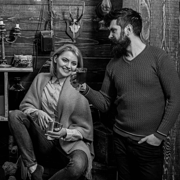 Woman and man on smiling faces enjoy cozy atmosphere with hot drinks. Couple spend pleasant evening, interior background. Family, couple in love enjoy vacation in gamekeepers house. Coziness concept - Fotoğraf, Görsel