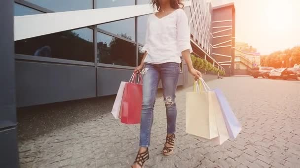 Sale, consumerism: Confident lady with shopping bags walking in a city. Slow motion. sunshine background - Video