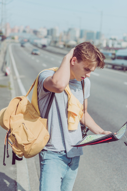 young man with map and backpack looking for destination - 写真・画像