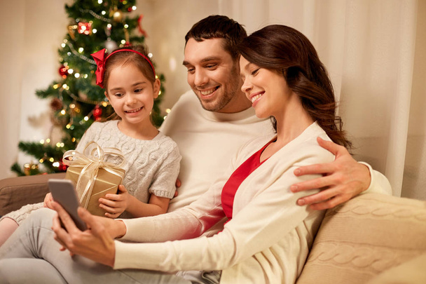 family with smartphone at home on christmas - Foto, Imagen