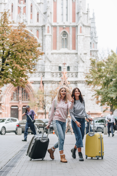 female tourists with backpacks and baggage walking on city street - Fotografie, Obrázek