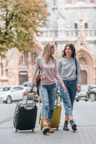 turistas do sexo feminino com mochilas e bagagem andando na rua da cidade
  - Foto, Imagem