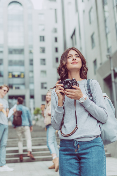 attractive girl with photo camera walking in urban city with friends - Photo, Image