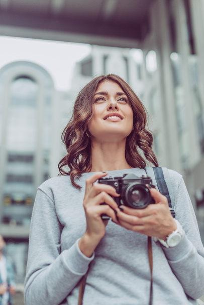 beautiful brunette tourist with photo camera in city - Fotó, kép