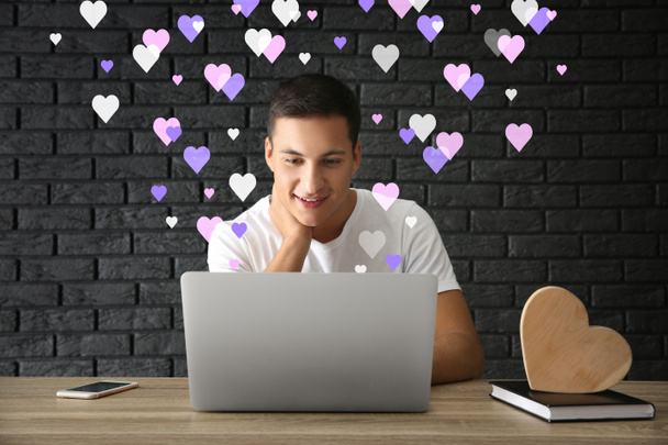 Hombre joven que usa el ordenador portátil para citas en línea en casa
 - Foto, imagen