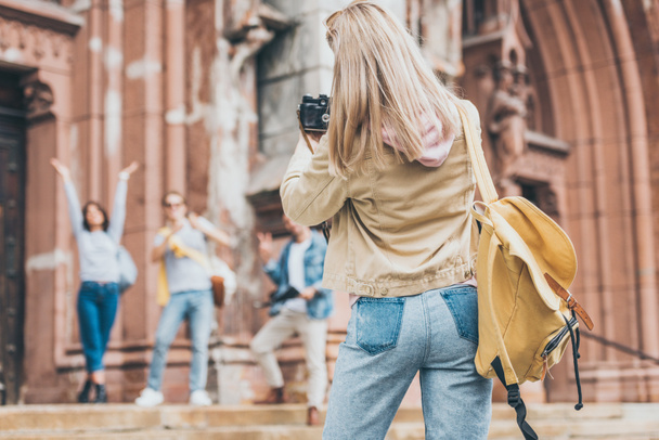 blonde woman taking photo of tourists on camera in city - Фото, зображення