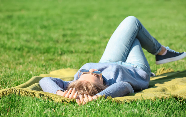 νεαρή γυναίκα που βρίσκεται στο πράσινο γρασίδι σε εξωτερικούς χώρους - Φωτογραφία, εικόνα