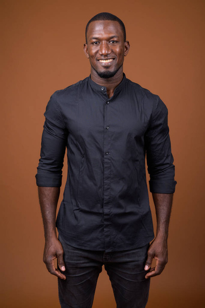Portrét pohledný africké podnikatele proti hnědým pozadím - Fotografie, Obrázek