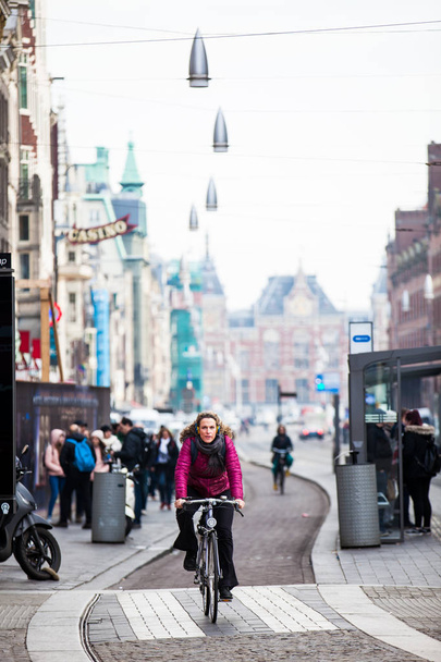 AMSTERDAM, NETHERLANDS- MARCH, 2018: Cyclist in a cold early spring day at the Old Central district of Amsterdam - Fotó, kép