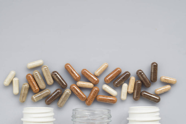 Medicinal capsule spill out of a three plastic bottles on a light surface - Foto, Imagem